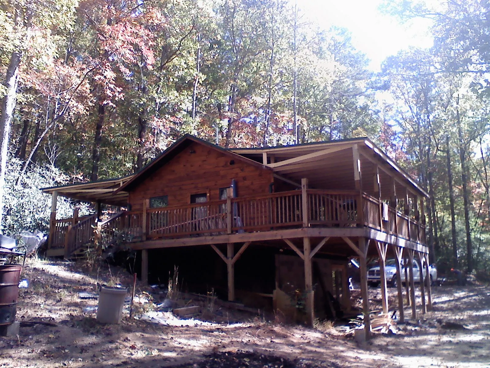 Log cabin with a wraparound porch and metal roof in the fall in Allenwood