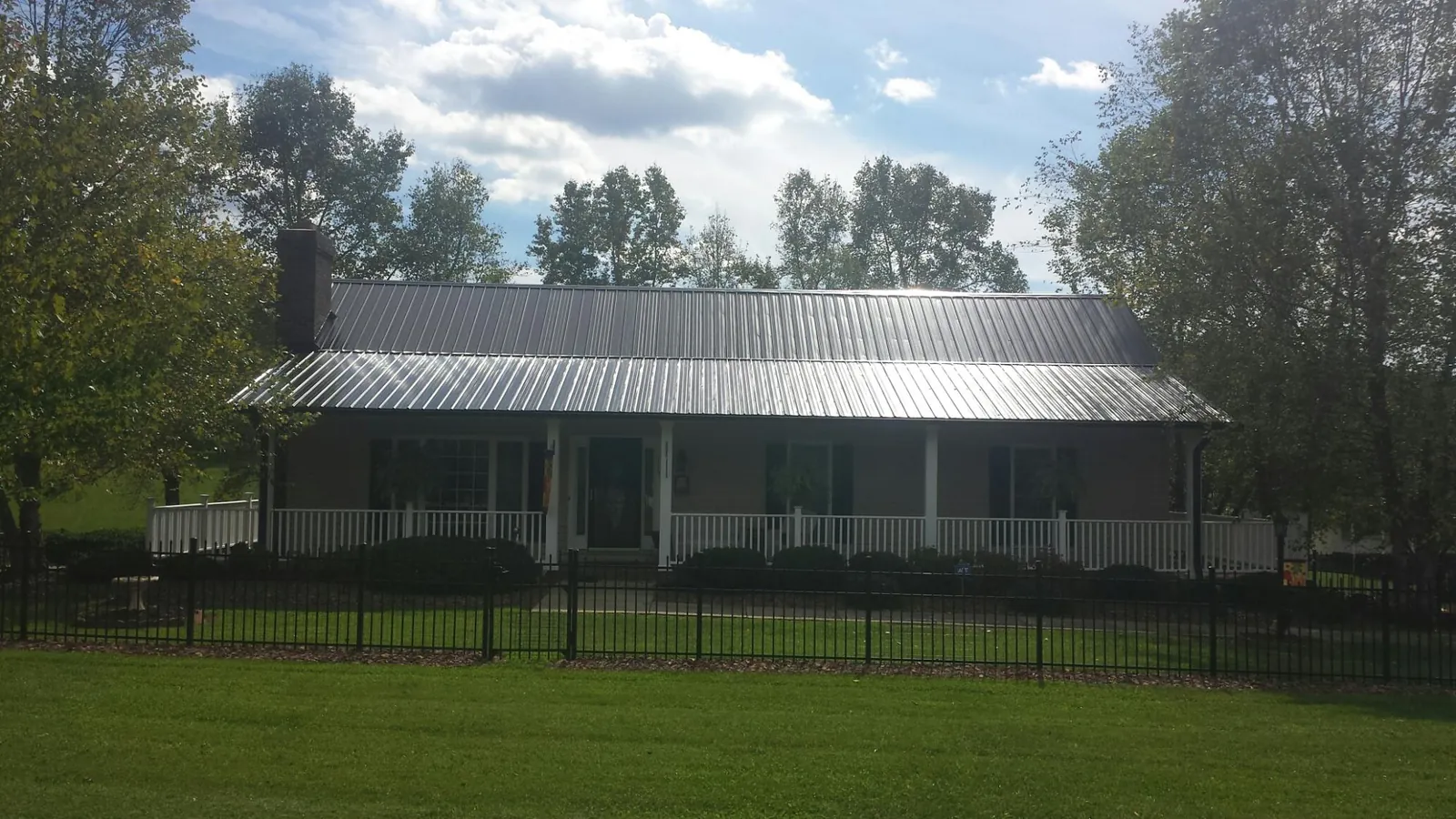 Gray metal roof on a brick ranch with a full width front porch — Gutter Guard Installation work by our crew in Allenwood
