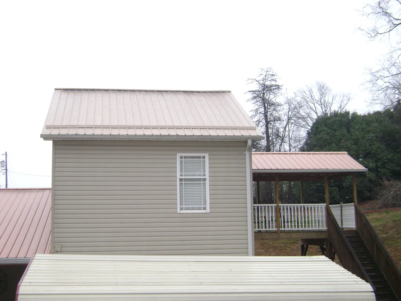 Tan metal roofs on a two story addition and attached porch, from a Roof Replacement job in Allenwood
