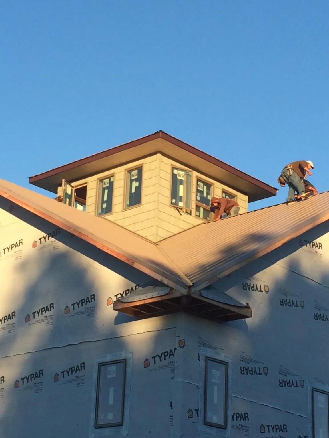 Roofers working around a rooftop cupola on a new metal roof at sunset — Roof Waterproofing in Allenwood by Roofing Brothers